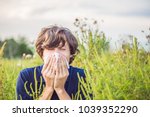 Young man sneezes because of an allergy to ragweed