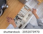 Top view closeup housewife hands tidying up cutlery in drawer general cleaning at kitchen. Woman neatly assembling fork, spoon, knife accessories for eating use Konmari storage organization method