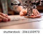 Small photo of Close up craftsman hands sew natural stuff blank for wallet use sewing machine with needle. Male tanner connecting details creating quality leatherwork accessories. Working process at leather workshop