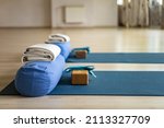 Small photo of Inventory ready training yoga Iyengar therapy. Sports props mat, wooden brick, plaid, belt and bolster weighting agent at classroom gym. Practicing harmony balance healthy lifestyle physical activity