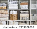 Bed linens closet neatly arrangement on shelves with copy space domestic textile Nordic minimalism comfortable storage. Rolled towels in straw basket duvet cover sheet pillow plaid in cupboard