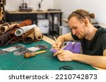 Small photo of Craftsman drawing shoe last pattern creating leatherwork at studio leather workshop. Male tanner at working process of creating handwork stuff use natural material and equipment at leather workshop