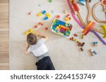 Small photo of Preschool baby boy playing wooden Montessori materials rainbow arch railways at childish room. Playthings storage cupboard arrangement organizing. Male kid with natural eco friendly toys at home.