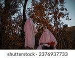 two sheet ghosts in front of trees