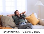 Happy beautiful young asian woman relaxing on sofa at home, enjoying weekend, comfortable in living room dreaming ,relax and chill out concept.