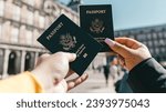 Small photo of Hand grasping a building in the city. holding a visa passport from the United States of America. visa passport held by two people in the city of fun. Two hands clasp and communicate, conveying.