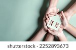 Small photo of Hands holding wooden house, family home, homeless housing, mortgage crisis and home protecting insurance, international day of families, foster home care, family day care, stay home concept