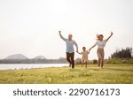 Small photo of Happy family in the park sunset light. family on weekend running together in the meadow with river Parents hold the child hands.health life insurance plan concept.