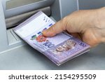 Small photo of A woman chooses Malaysian ringgit from an ATM, The highest denomination, A lot of money, Economic and financial concept, Rising cost of living