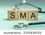 Small photo of SMA, spinal muscular atrophy, Written on wooden blocks, a rare disease in which, due to a genetic defect, neurons in the spinal cord responsible for muscle contraction and relaxation gradually die.