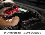 Check battery voltage with electric multimeter. Man using multimeter to measure the voltage of the batteries. Mechanic doing car inspection, he is testing car battery with tester.