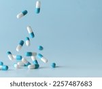 Falling blue medicine pill capsules on blue background. Antibiotics
