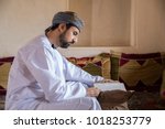 arab man in traditional omani outfit reading a book