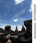 Small photo of An ancient beheaded buddhist statue with a view of bird, sky and pagoda