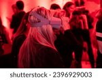 Small photo of Silhouetted in red radiance, a woman in profile navigates a virtual realm, surrounded by fellow enthusiasts, in a symphony of shared experiences at a cutting-edge tech event.