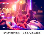 Girls having fun in electric bumper car in amusement park