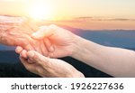 Small photo of Caregiver, carer hand holding elder hand with blurred nature background. Euthanasia Philanthropy kindness to disabled old people concept. National Senior Citizens Day