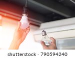 Power saving concept. Asia man changing compact-fluorescent (CFL) bulbs with new LED light bulb.
