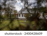 Small photo of An old house built at the beginning of the twentieth century captured on an autumn morning through the foliage of trees, as a look at the past from the future