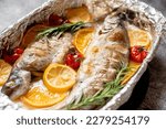 baked trout with lemon, orange, spices on a stone background