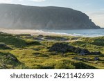 Small photo of A serene summer evening by the Barents Sea. Beautiful and warm summer evening light on the shoreline and sandy beach, Finnmark, Norway.