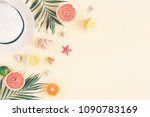 Summer composition. Fruits, hat, tropical palm leaves, seashells on pastel yellow background. Summer concept. Flat lay, top view, copy space