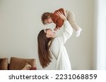 Happy cheerful young mother throws an adorable baby in air, plays, hugs baby with love, care, enjoys motherhood, maternity leave. Family spends time together.
