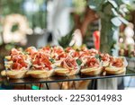 Small photo of catering buffet table with snacks and appetizers. Set of canapes with jamon, bruschetta, pear and cheese and mint