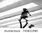 Shadow and silhouette of a teenage girl crossing the street at zebra crosswalk , upside down in black and white