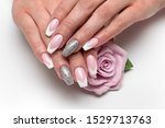 Wedding sharp French manicure with silver sequins on the ring fingers on a white background close-up on long nails with a pink rose in hand