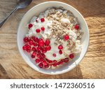 Small photo of Rustic cottage cheese with seeds and sour cream in a deep white plate on a wooden spile, from the upper angle