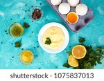 Small photo of Homemade sauce Mayonnaise and ingredients eggs, oil, lemon, mustar on blue background. Top view