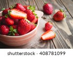 Fresh strawberries in a bowl on wooden table with low key scene.