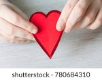 Small photo of A paper red heart connected from two disjoint halves. Two halves of the heart in the hands closeup.