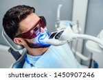 Dentist starting teeth whitening procedure with young man.