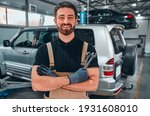 Small photo of Portrait of a young beautiful car mechanic in a car workshop, in the background of service. Concept: repair of machines, fault diagnosis, repair specialist, technical maintenance and on-board computer