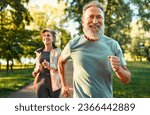 Cardio training. Close up of energetic fit sportsman spending morning in park and jogging together with wife. Active pensioners taking care of health and doing regular physical activities on nature.