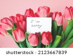 white card with the inscription i am sorry in a bouquet of beautiful tulips, the concept of apologies.