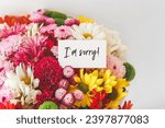 bright multi-colored bouquet of flowers with white card with the inscription i am sorry, the concept of apologies.