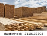 Industrial production of finished lumber products stacked in stacks on the warehouse territory. On an open background of blue sky with clouds.