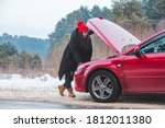 woman looking at engine broken car at winter road side