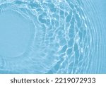 Small photo of Original beautiful background image in blue tint for creative work or design in form of water surface with diverging circular waves, play of light and shadow and space for text. Water texture.