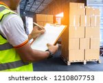 Worker Holds a Clipboard Checking the Loading Cargo Shipment at Distribution Warehouse. Forklift Loading Delivery to Customers. Package Boxes Supplies Warehouse. Freight Truck Logistics Transport 
