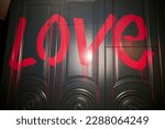 The inscription Love in red paint on the wall. The inscription Love in red paint with streaks on the wall. The word Love is written in tap paint with streaks on the wall
