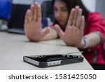 Selective focus of mobile phone battery explodes on table with blurred woman emotionally shocked in office. Blow up cellphone battery or explosive smartphone. Danger of using technology concept.