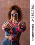 Small photo of Blurred chappy ethnic female in trendy clothes crossing sparklers while having fun against brown background