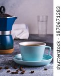 Small photo of A cup of coffee and Geezer coffee maker under blurred bokeh background