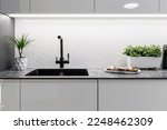 Small photo of Black kitchen sink and Tap water in the kitchen. The interior of the kitchen room of the apartment. Built-In Appliances. Kitchen Appliance. Domestic Appliances