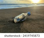 Small photo of Nestled in the golden sands, a bottle holds a plea for help. As the evening sun paints the sky with hues of warmth, this message in a bottle whispers tales of hope amidst the serene coastal embrace
