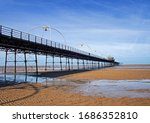 Small photo of Southport Pier, viewed from the beach with patterns of residual water in the foreground